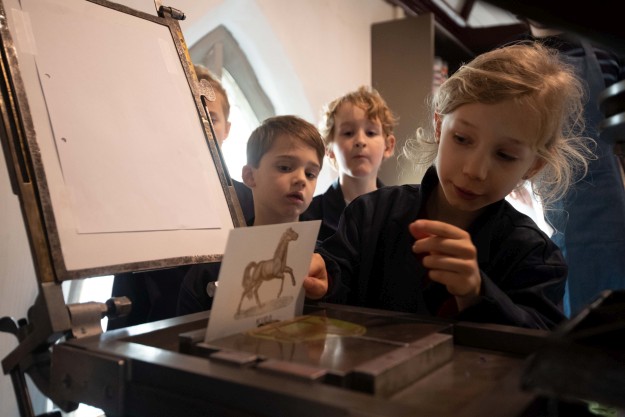 Kinderen maken een afdruk op een historische drukpers